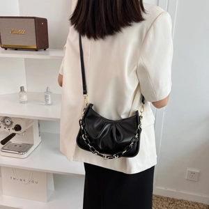 Chic black pleated cloud bag with chunky resin chain strap shown on shoulder