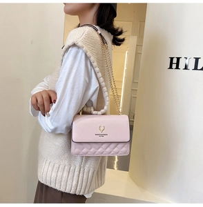 Detail of pink quilted leather bag featuring a golden deer head relief and chain strap