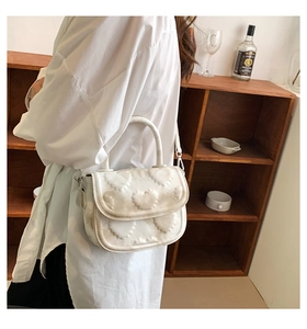 Détail d'un sac à main blanc avec texture cœur en relief et poignée ronde fixe