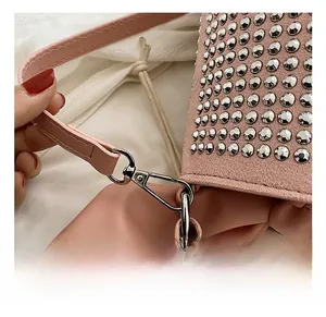 Close-up of pink leather bucket bag featuring silver studs and detachable metal hooks