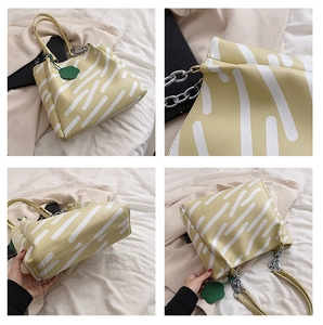 Close-up of yellow tote bag with abstract print, silver chain, and floral charm