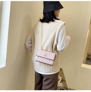 Model wearing a pink quilted crossbody bag with gold deer logo and chain strap detail