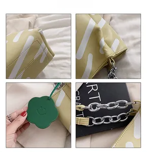 Detail view of large tote bag with striped pattern, floral charm and silver chain strap