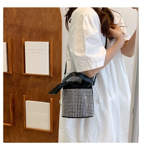 Detail of black rhinestone bucket bag with silver studs and white drawstring closure