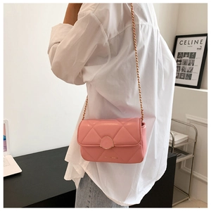 Sac bandoulière rose matelassé avec chaîne dorée porté à l'épaule sur une chemise blanche