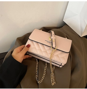 Detailed close-up of pink quilted crossbody bag with golden deer head logo and chain