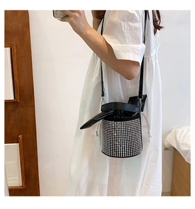 Detail of black rhinestone bucket bag with leather drawstring and thin shoulder strap