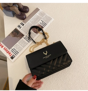 Close-up of black quilted shoulder bag with gold deer logo and metallic chain strap