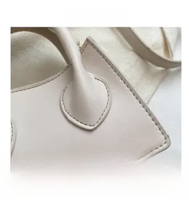Gros plan sur la texture du sac en cuir beige avec coutures précises et grainé