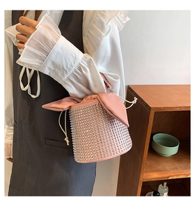 Detail of pink rhinestone bucket bag featuring rabbit ear flap and white drawstring closure