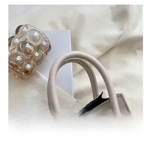 Détail d'un sac à main en cuir blanc crème avec poignée renforcée et finitions dorées