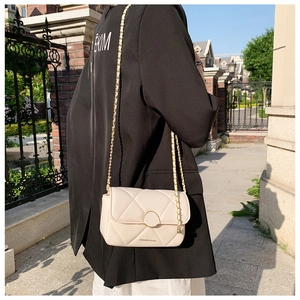 Détail du sac bandoulière crème avec fermoir doré et bandoulière chaîne sur le mannequin