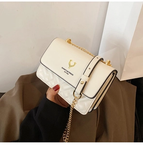 Close-up of white quilted crossbody bag with gold deer head logo and metal chain strap