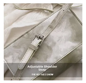 Detail view of the adjustable marble pattern shoulder strap on the chic cream crossbody bag