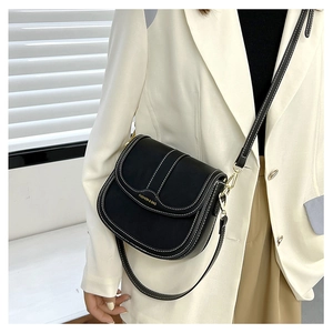 Detail of black saddle bag with white contrast stitching and gold fashion brand lettering