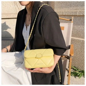 Détail du sac bandoulière matelassé jaune avec chaîne en métal et fermoir rond