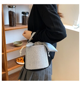 Detail showing shimmering silver rhinestone bucket bag with a chic grey drawstring bow