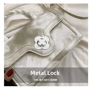 Detail of white marble pattern handbag featuring a gold four-petal flower metal clasp