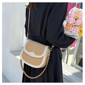 Detail of khaki saddle bag with white trim worn by a model in a lifestyle setting