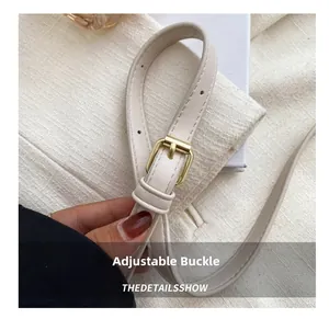 Détail macro d'une bandoulière de sac en cuir blanc crème avec boucle en métal doré clair