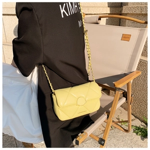 Photo en extérieur d'un sac matelassé jaune clair avec chaîne sur un mannequin, élégant