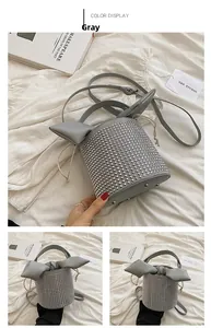 Detail of grey bucket bag with silver studs, rabbit ear lid, and drawstring closure