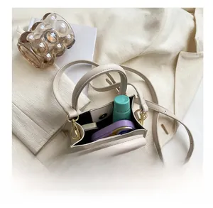 Détail intérieur du mini sac beige montrant sa capacité compacte et ses ferrures dorées