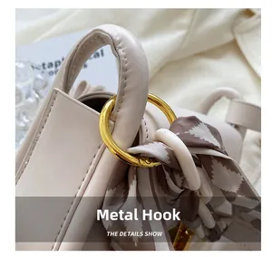 Détails de l'attache en métal doré et du foulard en soie sur sac bandoulière crème