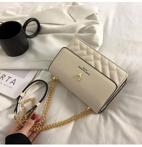 Detail of beige quilted shoulder bag with golden deer hardware and chain strap