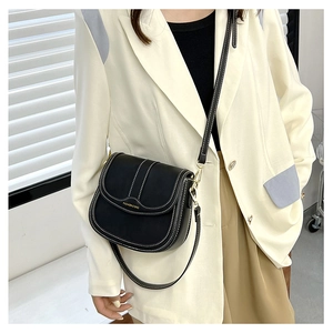 Detailed view of black saddle bag with contrast stitching and adjustable shoulder strap