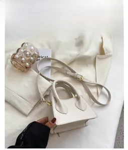 Détail d'un mini sac trapèze en cuir PU blanc avec finitions dorées et poignée