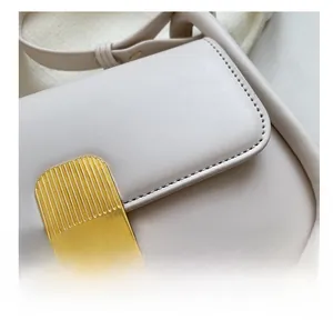 Gros plan du fermoir pivotant en métal doré et des coutures précises du sac beige en cuir