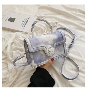 Detail of lavender cloud texture crossbody bag with floral clasp and woven handle