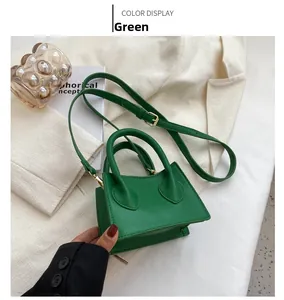 Détail du mini sac bandoulière vert avec ferrures dorées sur un tissu texturé blanc