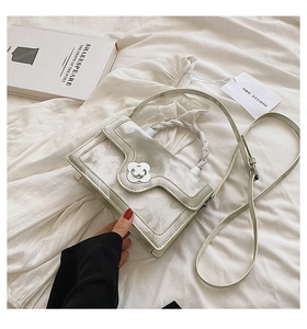 Detail of marble pattern handbag with floral buckle and woven handle on white fabric