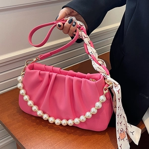 Pink pleated leather underarm bag featuring pearl chain strap and decorative silk scarf