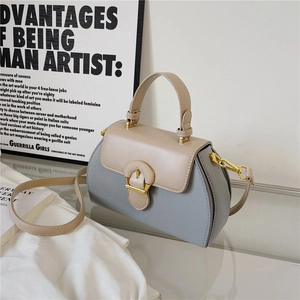 Detail of blue-grey and beige leather handbag with textured grain and gold buckle