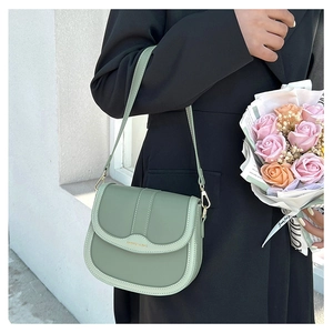 Detail view of sage green saddle bag with gold lettering and adjustable shoulder strap