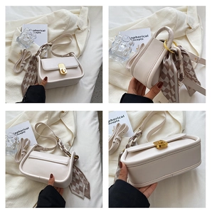Détails du sac bandoulière en cuir crème avec fermoir doré et foulard en soie à carreaux