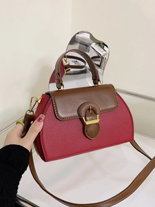 Detail of red lychee leather handbag with brown flap and contrasting buckle