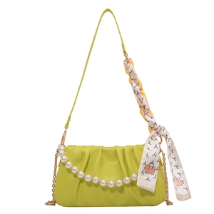 Green pleated crossbody bag with pearl chain and silk scarf on white background