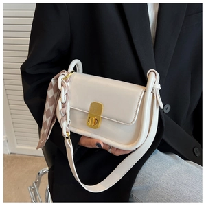 Détail du sac crème avec fermoir doré et chaîne en foulard de soie porté par un mannequin
