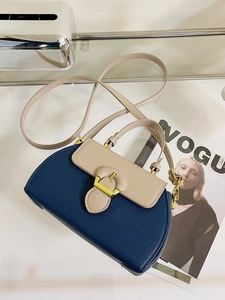 Detail of blue and beige leather crossbody bag with gold buckle on a vogue magazine