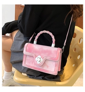 Detail of pink marble pattern handbag with flower clasp and braided handle on model