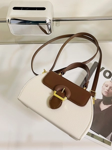 Close-up of white lychee leather and brown trim on a stylish dual-tone handbag