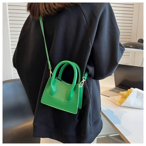 Détail d'un mini sac à main en cuir PU vert vif porté par un mannequin en sweat à capuche