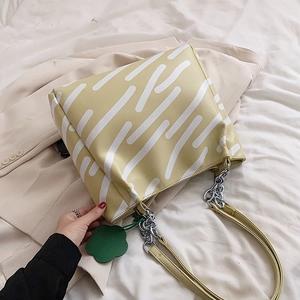 Large yellow tote bag with white stripes and metal chain strap on beige blazer