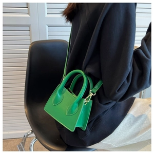 Mini sac à main vert vif avec poignée ronde présenté dans un cadre de style de vie