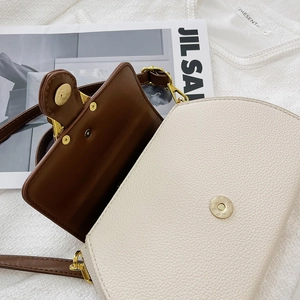 Detail view of contrast leather texture and golden magnetic buckle on the square handbag