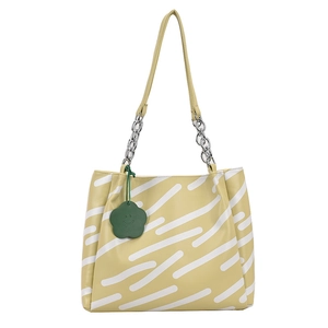 Pale yellow striped tote bag with silver chain and a green flower charm on white background